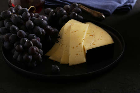 cheese and black grapes on a plateの写真素材