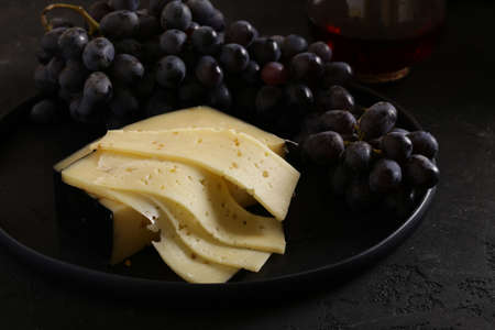 cheese and black grapes on a plateの写真素材