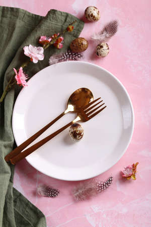 Easter still life table setting flowers and eggs on a pink background