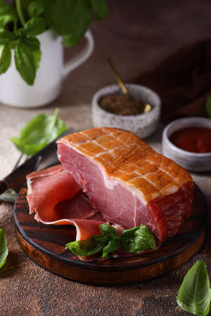 piece of raw smoked prosciutto ham on a wooden boardの写真素材
