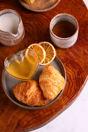 breakfast with croissants and honey on the tableの写真素材