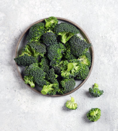 fresh broccoli vegetables in a gray plate on a light gray background top view