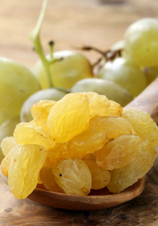 organic light white grape raisins in wooden spoonの写真素材