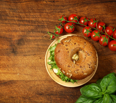 bagel with salad and cheese on a wooden boardの写真素材