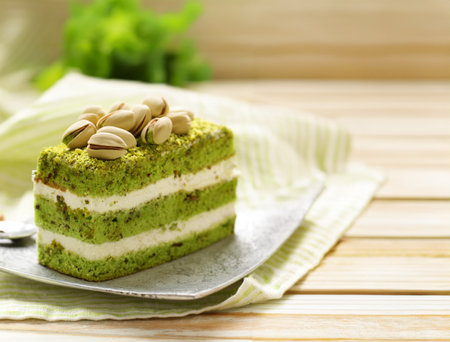 piece of pistachio green cake with cream and nutsの写真素材