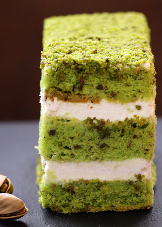 piece of pistachio green cake with cream and nutsの写真素材