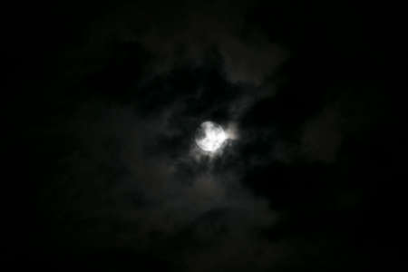 full moon with bright clouds and the moon as a spotlight in a dark night sky in bavaria