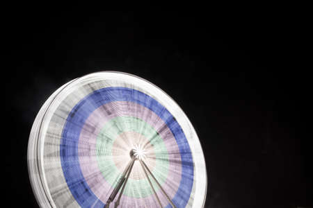 Big ferris wheel at a festive festival with smoke and lighting in various colors at night spinning long exposureの写真素材
