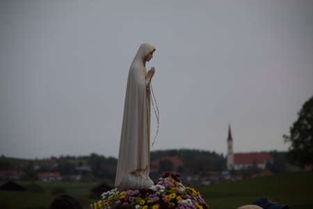 Statue of praying mary on flowers at a pilgrims walk