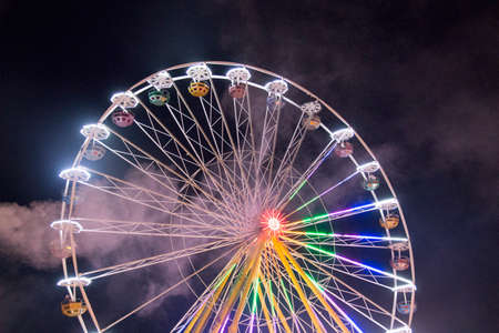 ferris wheels spinning with colorful lightpainting on a bavarian fair in germany at night, shot with long exposure and dust and smokeのeditorial素材