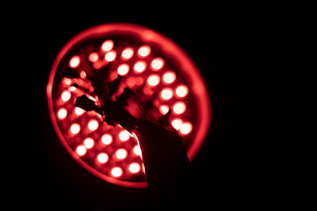 black silhouette of guitar head stock in front of dark red led lightの写真素材