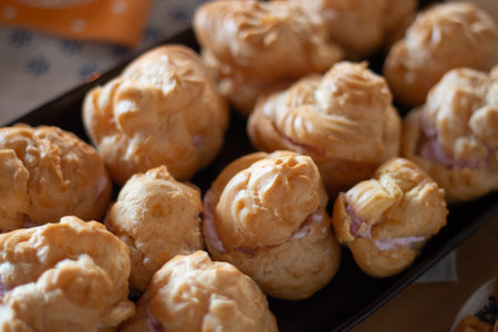 Freshly Baked Cream Puffs Arranged on Trays, Highlighting Their Golden and Fluffy Textureの写真素材