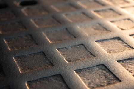 Cast iron manhole cover on cobblestone street in warm light-urban texture