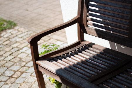 Wooden garden bench with strong sunlight and shadows-outdoor furnitureの写真素材