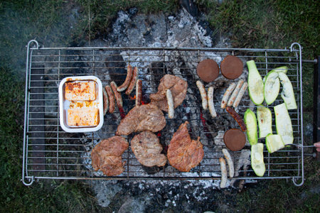 Meat and vegetables cooking on a portable barbecue grill-outdoor cookingの写真素材