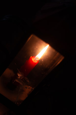 Candle flame glowing in darkness during Easter vigil ceremony with warm light and spiritual...
