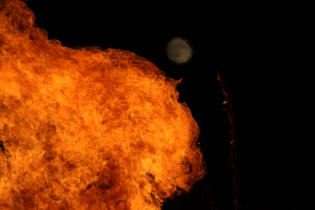 Large bright bonfire with distant moon at night-outdoor energyの写真素材