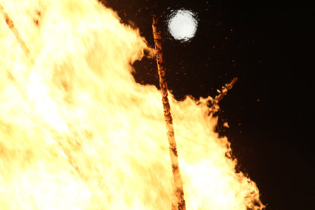 Full moon over a large bonfire with bright orange flames at nightの写真素材