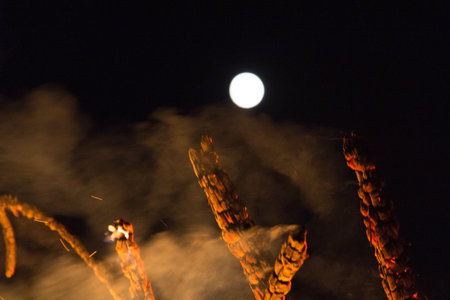 Full moon over a large bonfire with bright orange flames at nightの写真素材