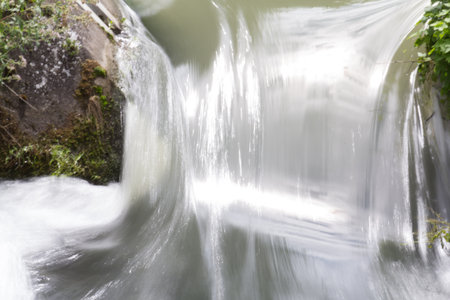 Flowing white water of a small waterfall with long exposureの写真素材