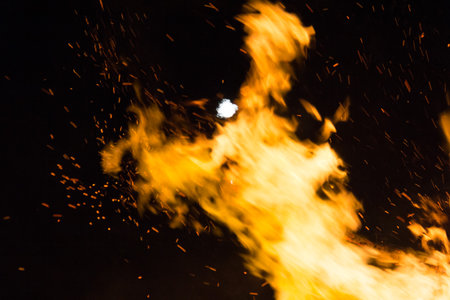 Full moon over a large bonfire with bright orange flames at nightの写真素材