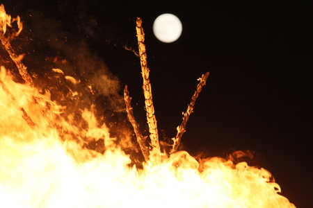 Full moon over a large bonfire with bright orange flames at night