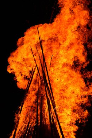 Large bonfire with bright orange flames against a dark night sky