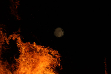 Large bonfire with intense orange and yellow flames burning wood