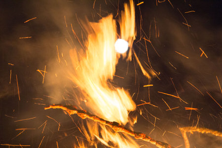 Large bonfire with intense orange and yellow flames burning woodの写真素材
