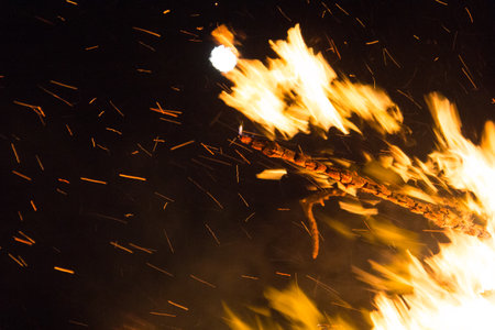 Large bonfire with intense orange and yellow flames burning wood