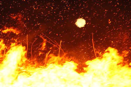 Large bonfire with intense orange and yellow flames burning wood