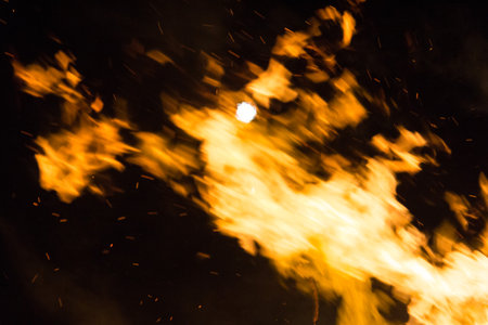 Large bonfire with intense orange and yellow flames burning woodの写真素材