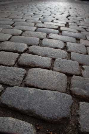 Dry cobblestone pavement with rough surface texture lit by angled light in moody low perspectiveの写真素材