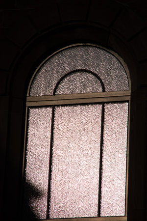 Textured arched window with frosted glass and soft backlight in dark interior