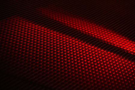 Red and black textured surface with diagonal light shadows in abstract pattern