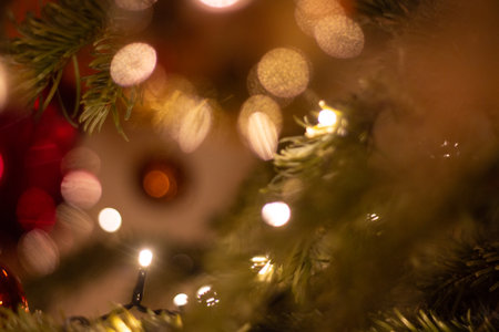 Abstract blurred background with warm bokeh lights and pine branches creating a festive holiday moodの写真素材