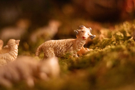 Miniature sheep figurines on moss in nativity scene setting with soft warm lighting
