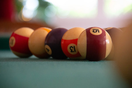 Close-up of billiard balls on green pool table with soft indoor lighting and shallow focusの写真素材