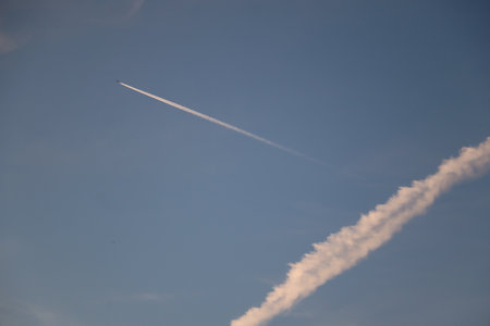 Diagonal airplane contrail across clear blue sky over Wasserburg am Inn in the evening lightの写真素材