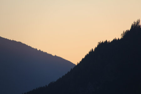 Mountain silhouettes at sunset with forest slopes in Tyrol Austriaの写真素材