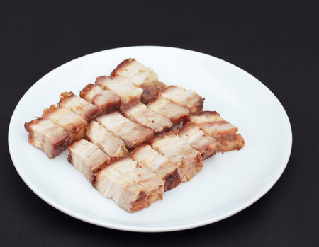 Roasted pork cut into pieces on a white plate.の写真素材