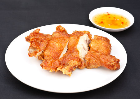 Fried chicken cut into pieces with spicy, sour and sweet sauce on white plate.の写真素材