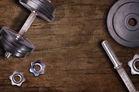 Weights at the gym whit handle and barbell. Stel gym equipment on dark wood floor background.の写真素材