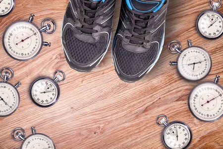 Running equipment. Stopwatch and running men shoes. Time for run. Sport running accessories on the wooden floor. Sports rivalry.Together running is cool.の写真素材