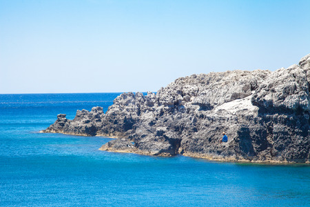 Angler fishing on the shore. Beach off the coast of the island in Greece. Seaside landscape. Rocky coast and sea.のeditorial素材