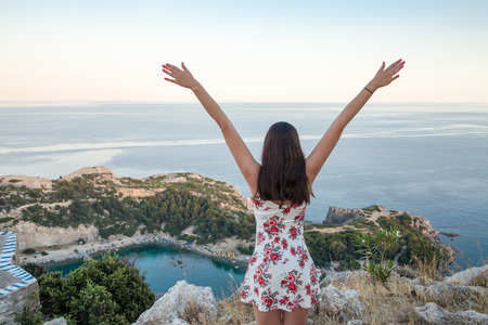 View from top on Anthony Quinn Bay and beach, Rhodes in Faliraki, Greece. Happy girl Raising One Hand. Beautiful beach and bay on the island of Rhodes. の写真素材