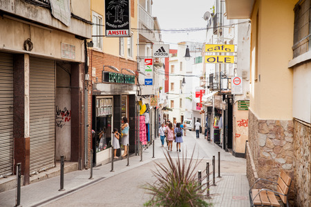 Shops and cafes near the narrow streets of Lloret de Mar. Downtown of Lloret, Spain. Tourists walking the streets of the city.のeditorial素材