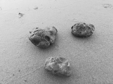 Three stones on sand beach black and white monochrom