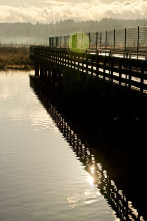 A pier in a lake with sun reflectionの写真素材