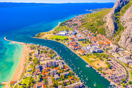 Aerial view of Omis, Croatia, showcasing the stunning confluence of the Cetina River and the Adriatic Sea, surrounded by dramatic cliffs, and the historic beauty of this placeの写真素材